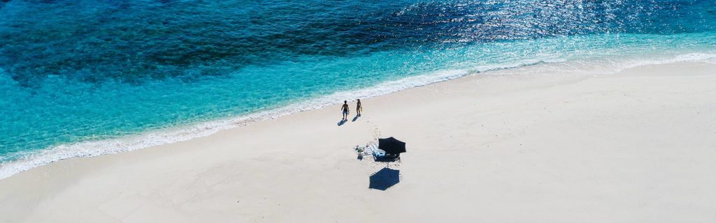 Drone shot of a couple walking on the beach at Yasawa Island Resort in Fiji