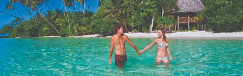 Romance in Samoa: Couple swimming  in front of traditional Samoan Fale. 