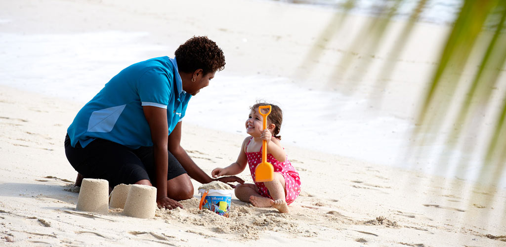 A nanny playing with a kid on a beach in Fiji.
